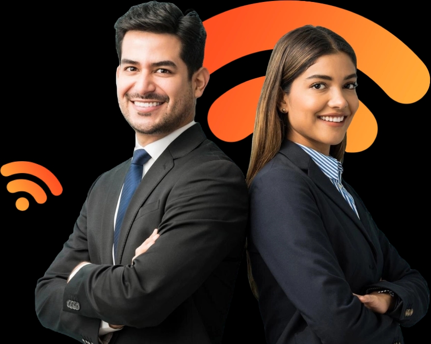 Um homem e uma mulher estão lado a lado, de costas um para o outro, ambos sorrindo. O homem tem cabelos escuros e curtos, veste um terno preto com gravata azul e camisa branca. A mulher tem cabelos castanhos compridos, usa um blazer preto, camisa listrada azul e branca. Ambos têm uma postura confiante, com os braços cruzados, parecendo profissionais em um ambiente de trabalho formal.